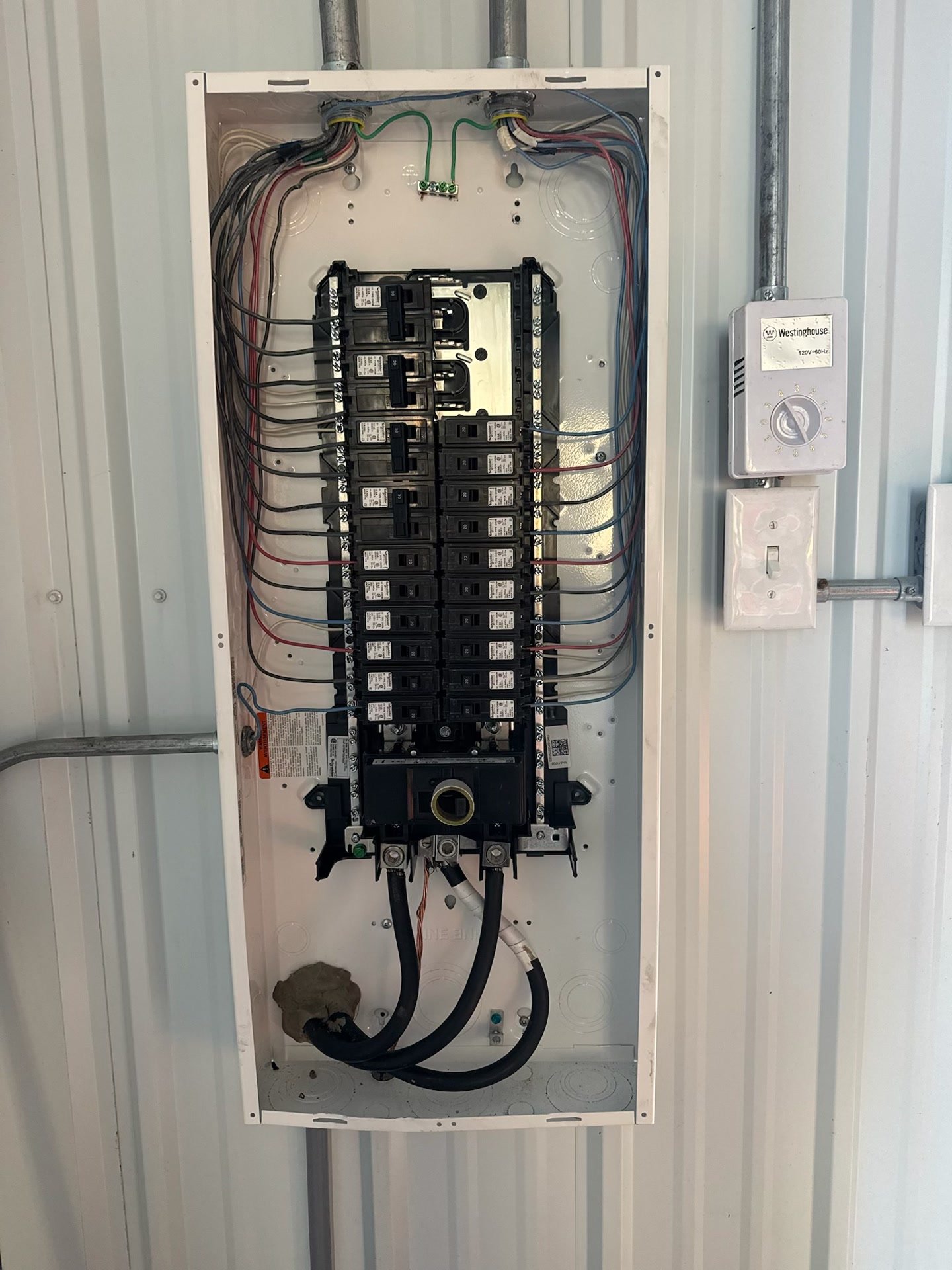 A breaker panel mounted on a steel wall, wired and landed neatly.